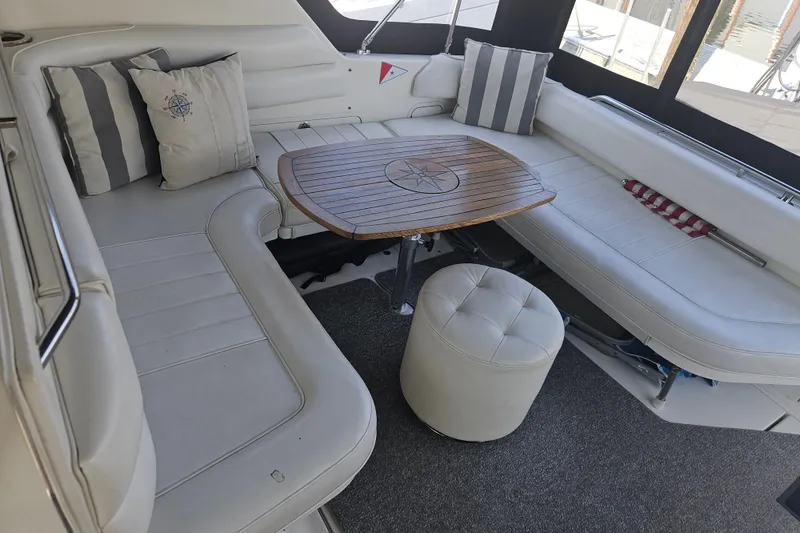 Slide: The Image of 1996 Sea Ray 370 Express Cruiser interior with cushioned seating and wooden table. - 20