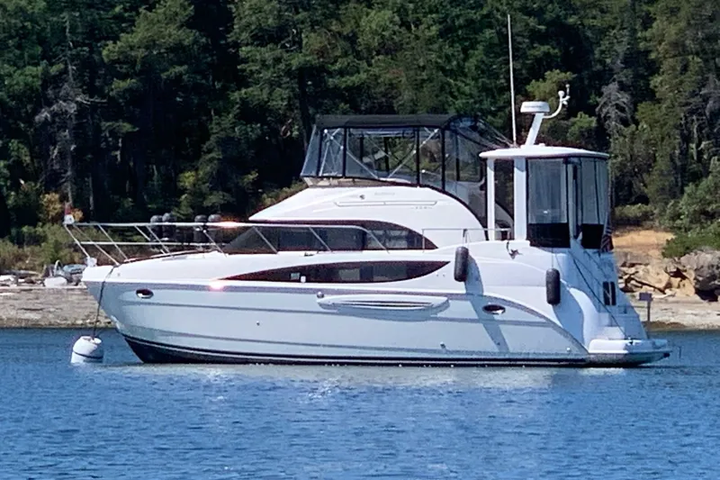 The Image of 2005 Meridian 368 Motoryacht anchored on a serene lake with forested background. - 0