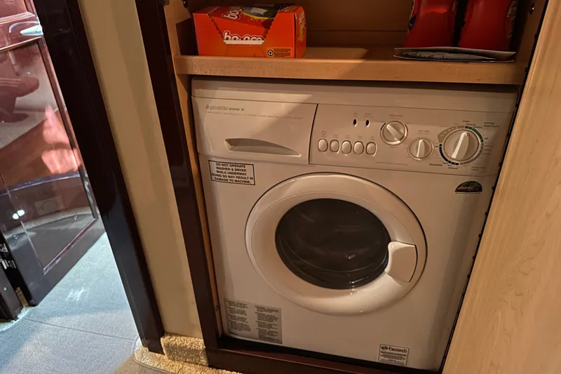 Slide: The Image of Compact washing machine inside 2007 Sea Ray 48 Sundancer yacht, with storage shelf above. - 50
