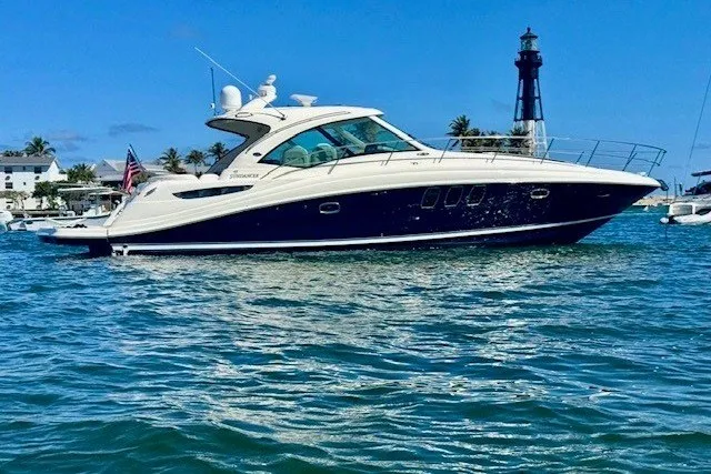 The Image of 2007 Sea Ray 48 Sundancer yacht cruising near a lighthouse on a sunny day. - 0