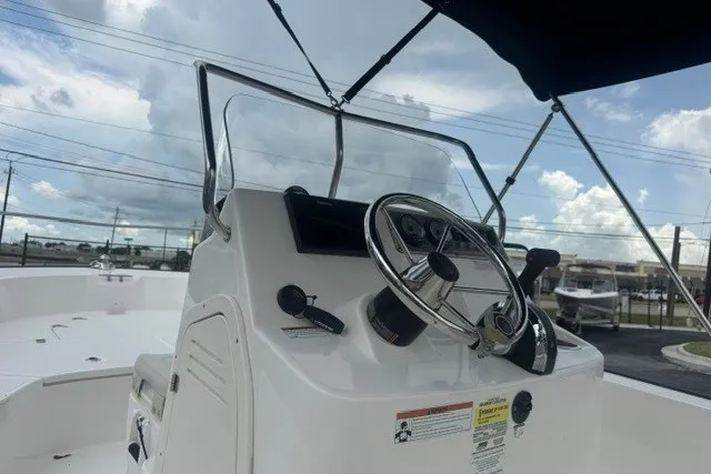 Slide: The Image of 2022 Boston Whaler 190 Montauk boat console with steering wheel and controls under cloudy sky. - 10