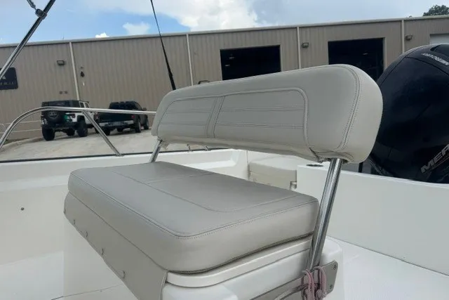 Slide: The Image of 2022 Boston Whaler 190 Montauk boat seat with cushioned backrest, docked near industrial buildings. - 11