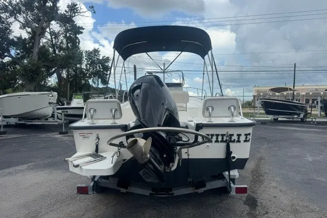 Slide: The Image of 2022 Boston Whaler 190 Montauk boat with outboard motor, parked outdoors under cloudy sky. - 3
