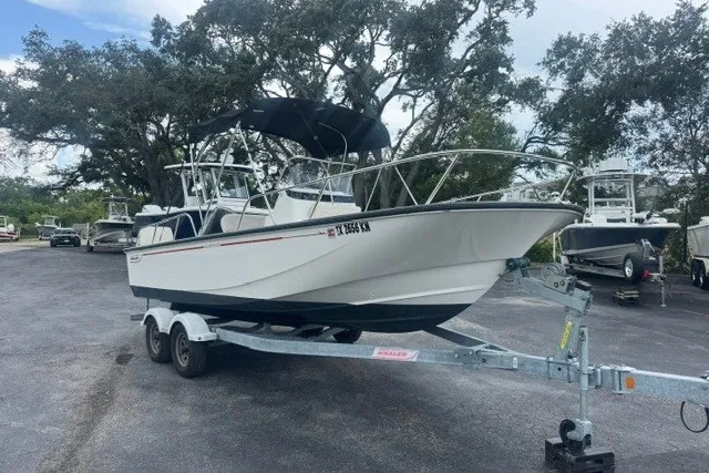 Slide: The Image of A 2022 Boston Whaler 190 Montauk on a trailer, surrounded by trees and other boats. - 4
