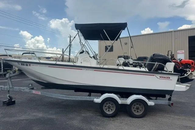 Slide: The Image of 2022 Boston Whaler 190 Montauk boat on trailer, parked outdoors under a cloudy sky. - 5