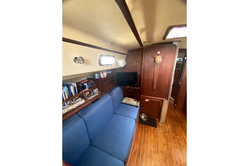 Slide: The Image of Interior of 1989 Island Packet 35 sailboat with blue seating and wooden cabinetry. - 7
