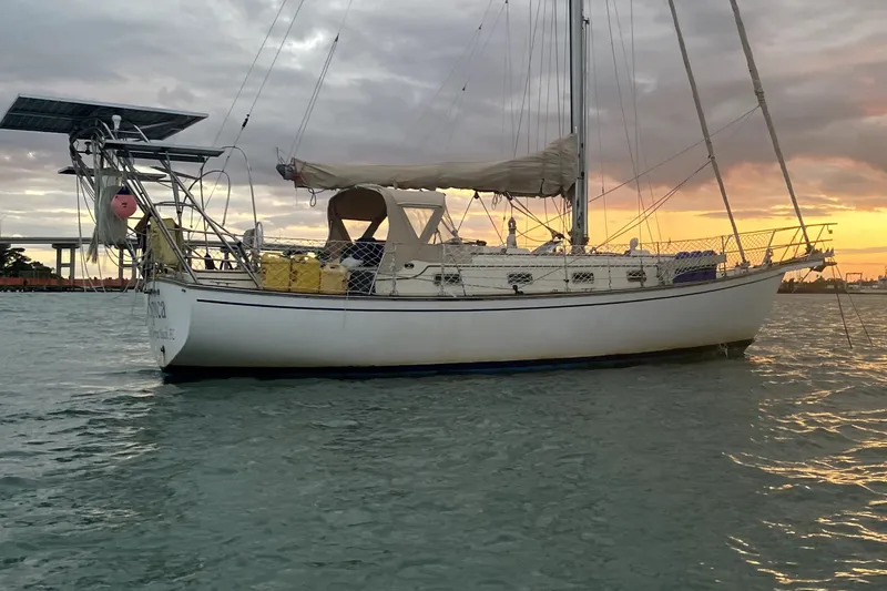 Slide: The Image of 1989 Island Packet 35 sailboat anchored at sunset on calm waters. - 11