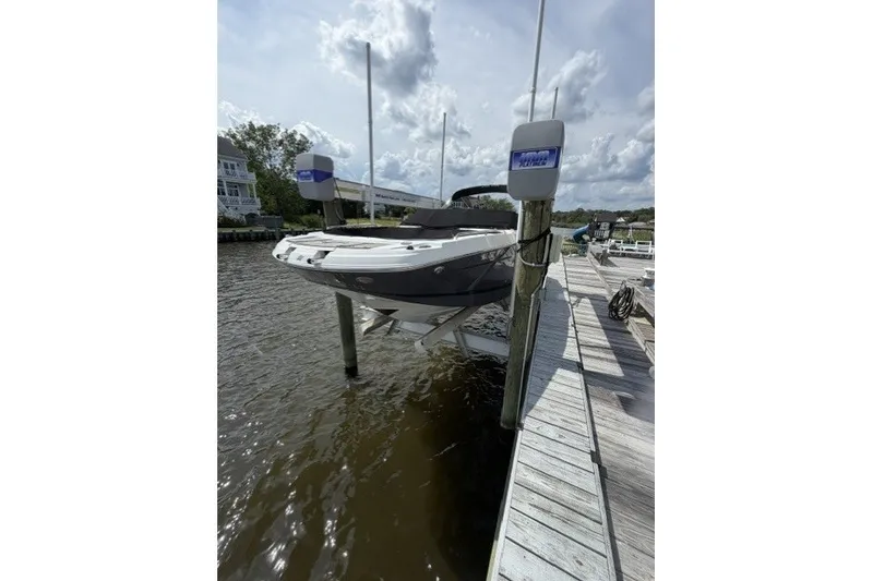 Slide: The Image of 2022 Four Winns HD5 OB boat docked on a lift by a wooden pier. - 2