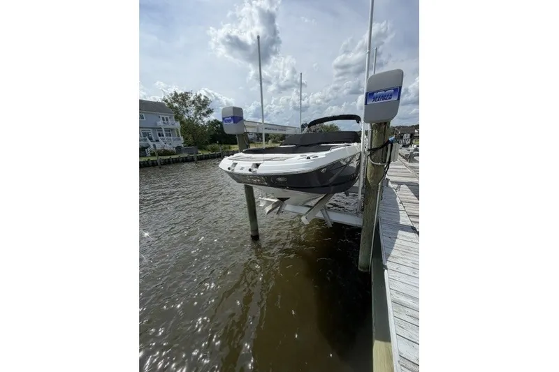 The Image of 2022 Four Winns HD5 OB boat docked on a lift by a waterfront. - 0