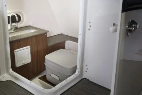 Slide: The Image of Manufacturer Provided Image: 2022 Four Winns HD5 OB boat interior with compact bathroom and seating area. - 11