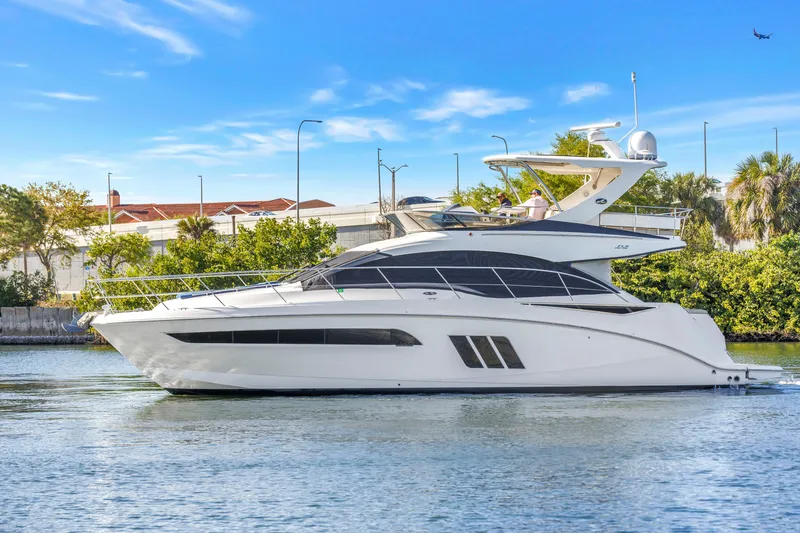 Slide: The Image of 2016 Sea Ray 510 Fly yacht cruising on a sunny day, surrounded by greenery. - 1