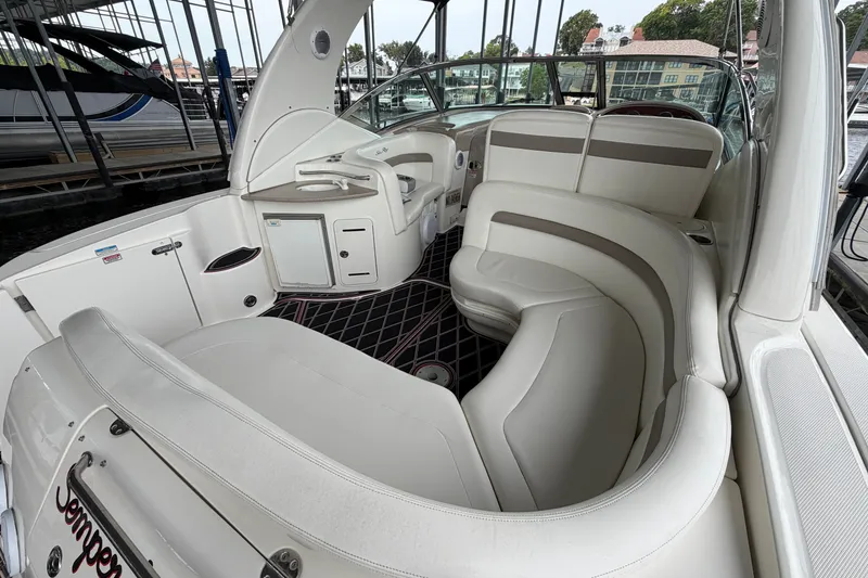 Slide: The Image of 2003 Sea Ray Sundancer 320 interior with white seating and helm, docked in marina. - 13