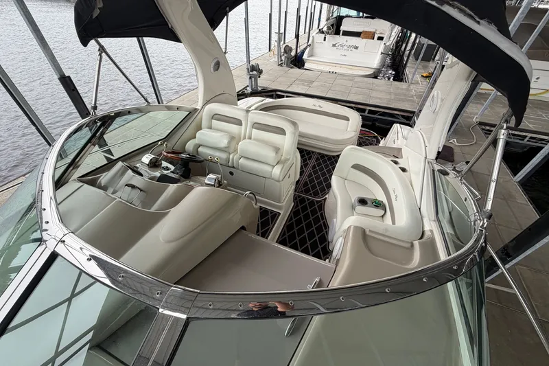 Slide: The Image of 2003 Sea Ray Sundancer 320 boat interior with plush seating and helm, docked at marina. - 24