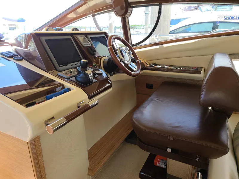 Slide: The Image of Azimut 47 2011 yacht helm station with leather seat, navigation controls, and wooden accents. - 12