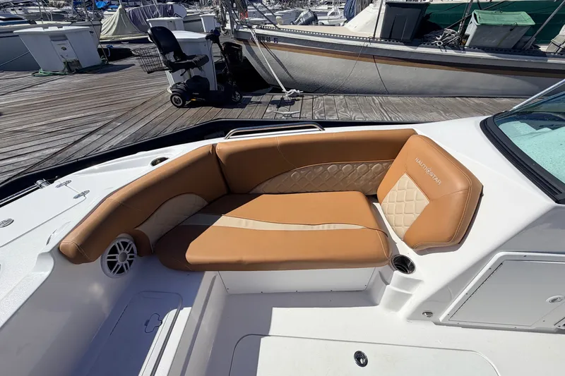 Slide: The Image of 2026 NauticStar 203 DC Deck boat with tan seating at a marina dock. - 22