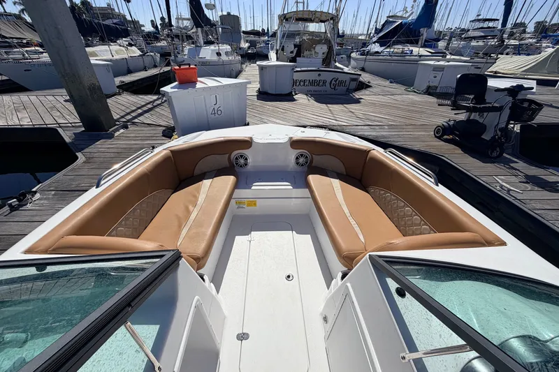 Slide: The Image of 2026 NauticStar 203 DC Deck boat with tan seating at a marina dock. - 18