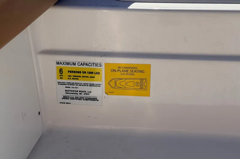 Slide: The Image of Capacity label on 2026 NauticStar 203 DC Deck boat, showing seating and weight limits. - 19
