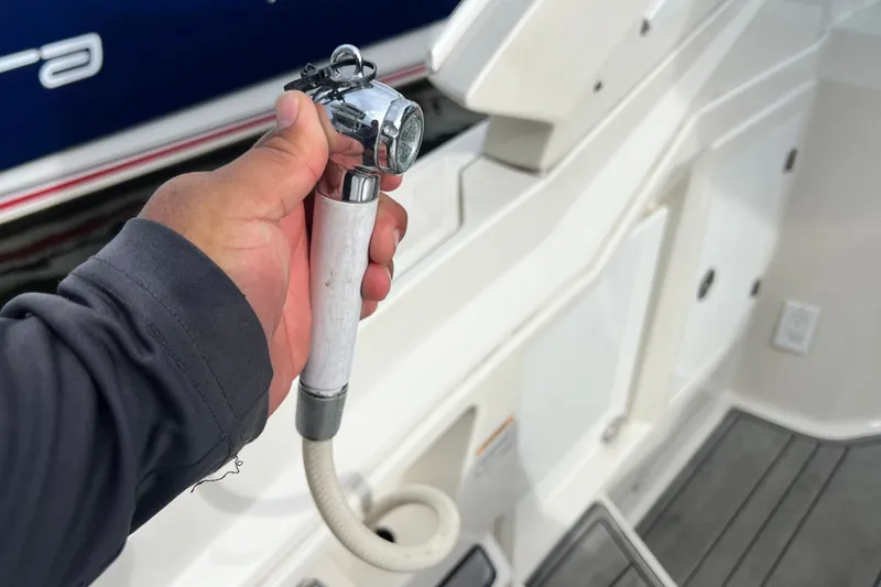 Slide: The Image of Hand holding a shower nozzle on a 2011 Monterey 328SS Super Sport boat deck. - 24