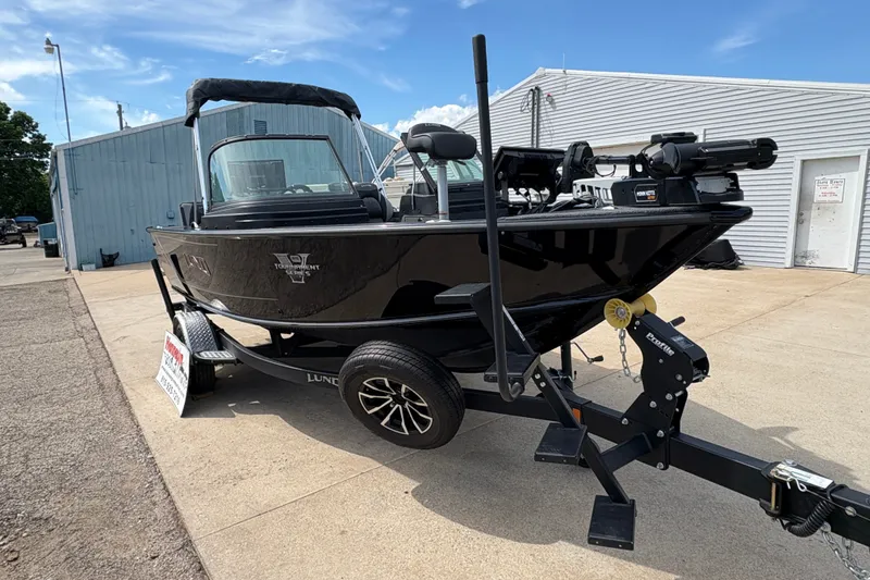 Slide: The Image of 2025 Lund 1875 Pro-V boat on trailer, parked outdoors near buildings. - 6