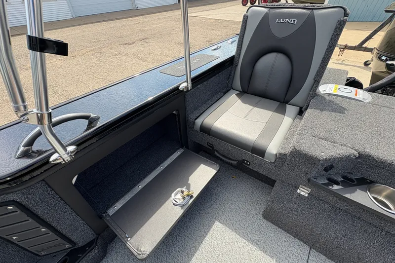 Slide: The Image of 2025 Lund 1875 Pro-V boat interior with storage compartment and cushioned seat. - 33