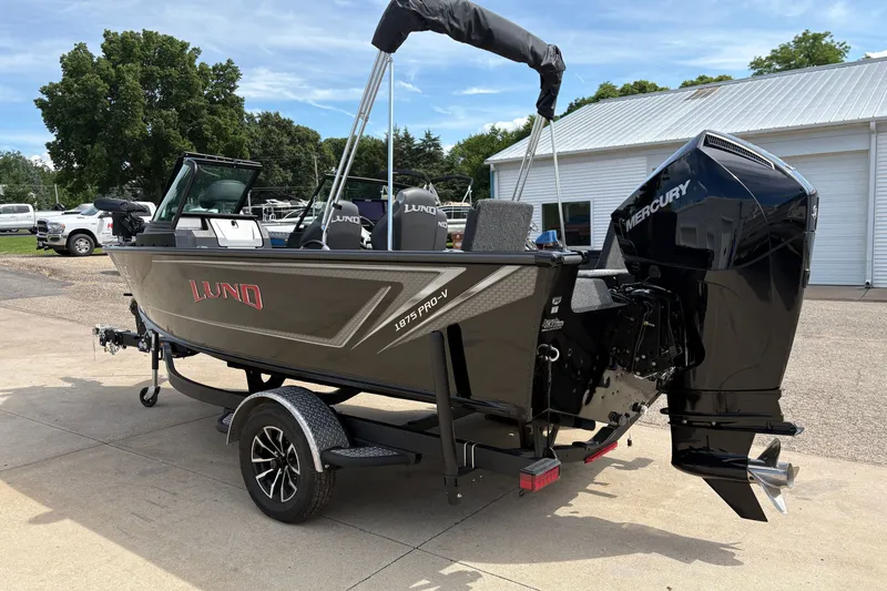 Slide: The Image of 2025 Lund 1875 Pro-V boat with Mercury engine on trailer, parked outdoors. - 4