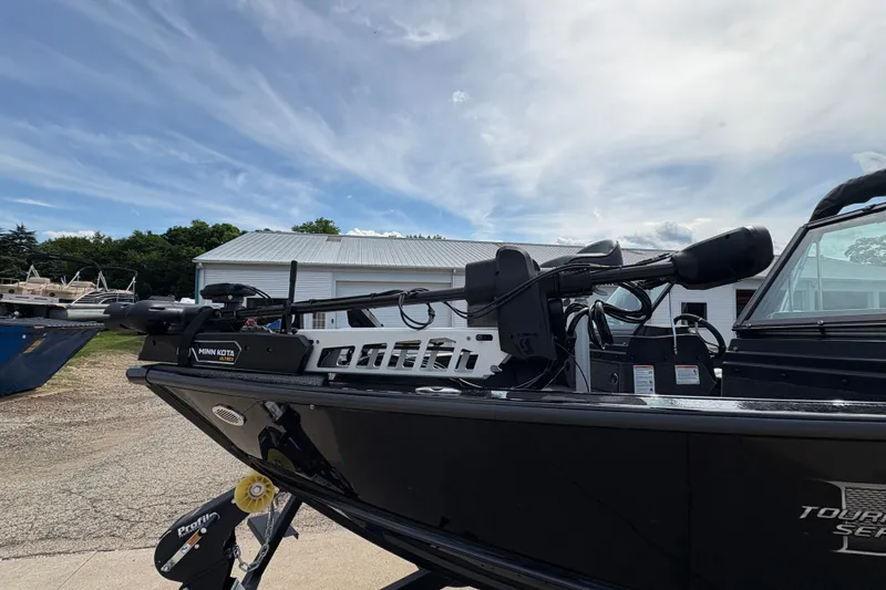 Slide: The Image of 2025 Lund 1875 Pro-V boat with Minn Kota trolling motor, parked outdoors under a cloudy sky. - 8