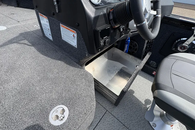 Slide: The Image of 2025 Lund 1875 Pro-V boat interior with open storage compartment and steering wheel. - 24