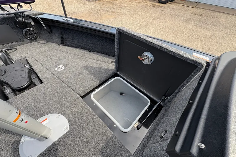 Slide: The Image of 2025 Lund 1875 Pro-V boat interior with open storage compartment and carpeted flooring. - 15