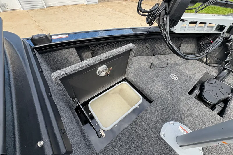 Slide: The Image of 2025 Lund 1875 Pro-V boat interior with open storage compartment and carpeted flooring. - 14