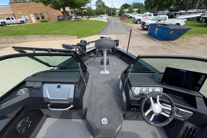 Slide: The Image of 2025 Lund 1875 Pro-V boat interior with steering wheel and dashboard, parked outdoors. - 18