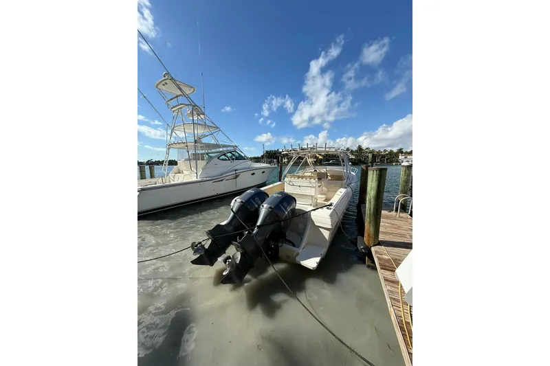 Slide: The Image of 2008 Intrepid 370 Cuddy boat docked with triple outboard engines under a clear blue sky. - 2