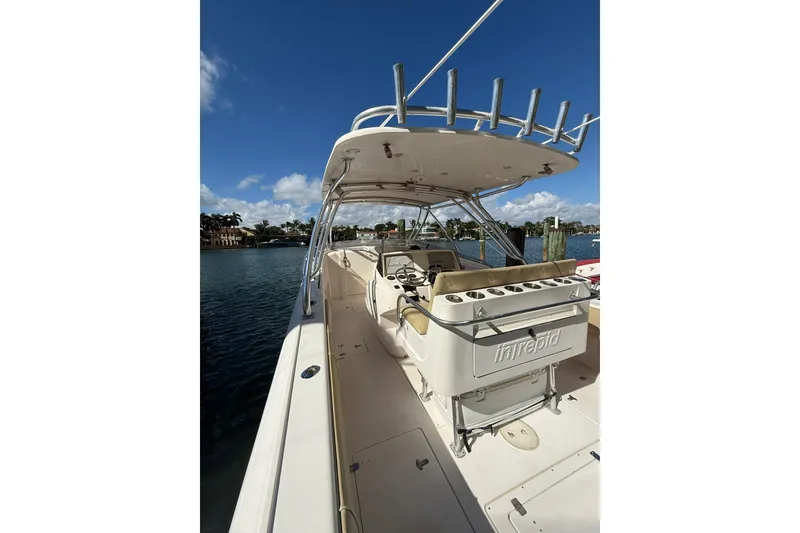 Slide: The Image of 2008 Intrepid 370 Cuddy boat docked, showcasing helm and seating area under clear blue sky. - 9