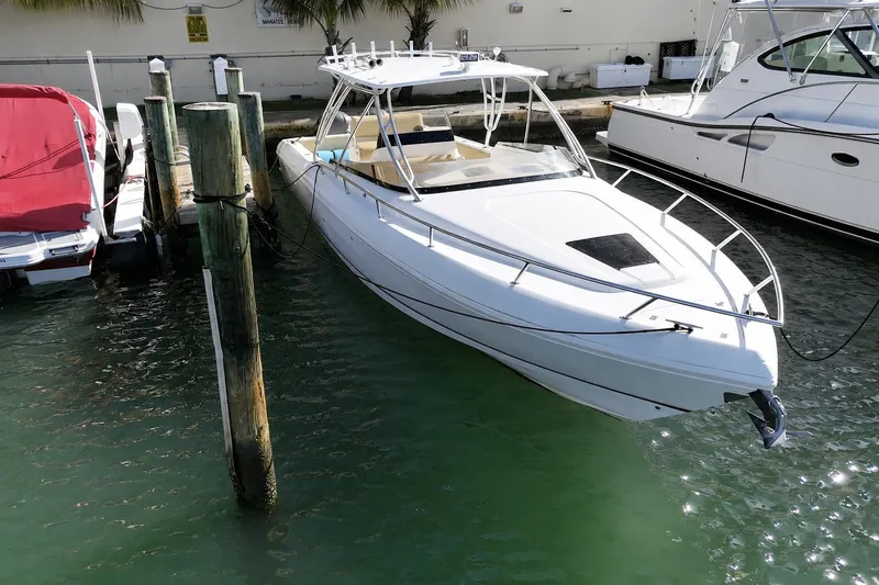 The Image of 2008 Intrepid 370 Cuddy boat docked in marina, surrounded by calm water. - 2