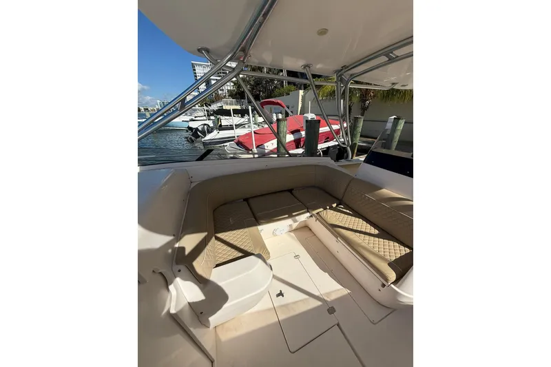 Slide: The Image of 2008 Intrepid 370 Cuddy boat interior with cushioned seating, docked near other boats. - 32