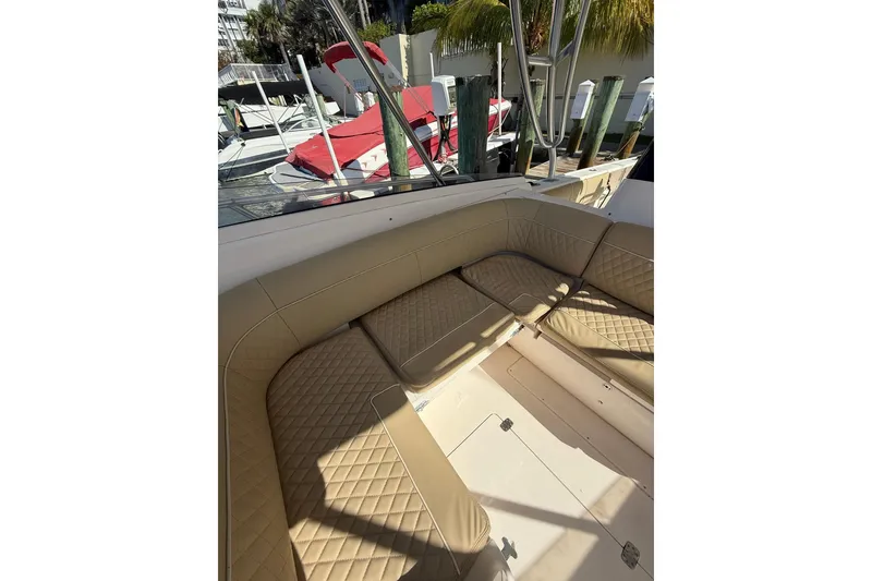 Slide: The Image of 2008 Intrepid 370 Cuddy boat with tan cushioned seating and docked boats in background. - 33
