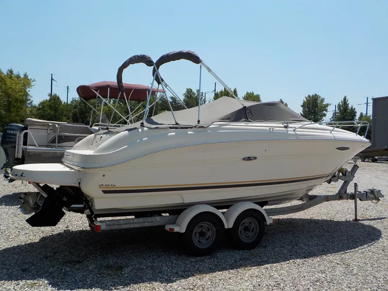 The Image of A 2004 Sea Ray 225 Weekender on a trailer in a gravel lot. - 1