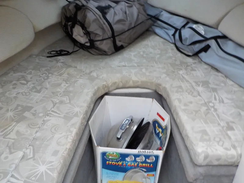 Slide: The Image of The interior of a 2004 Sea Ray 225 Weekender features cushioned seating and camping gear. - 22