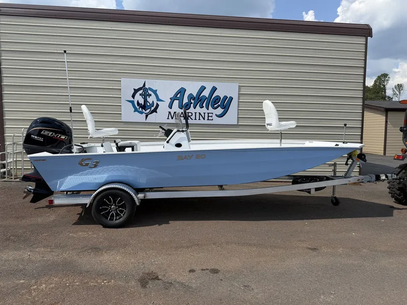 The Image of A light blue G3 Bay 20-115SHO boat on a trailer in front of a building with "Ashley Marine" sign. - 1