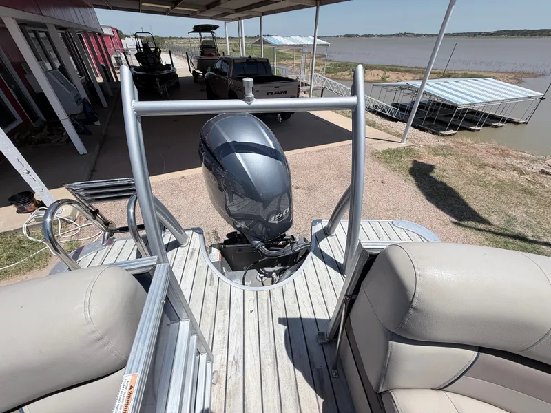 Slide: The Image of A 2018 Trifecta pontoon boat with an outboard motor, docked by a lakeside. - 20