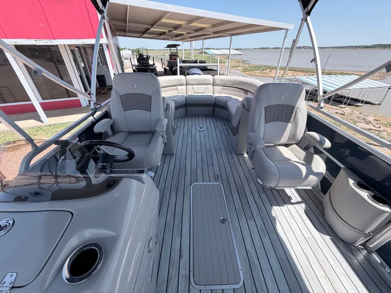 Slide: The Image of A 2018 Trifecta pontoon boat with gray upholstery and a spacious deck by the water. - 10