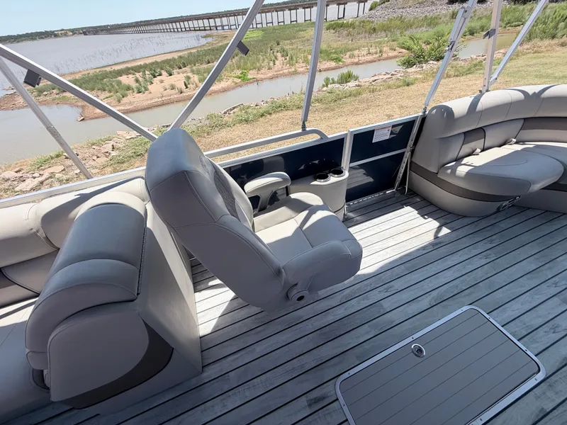 Slide: The Image of The image shows the interior of a 2018 Trifecta pontoon boat with gray seating and wooden flooring. - 14