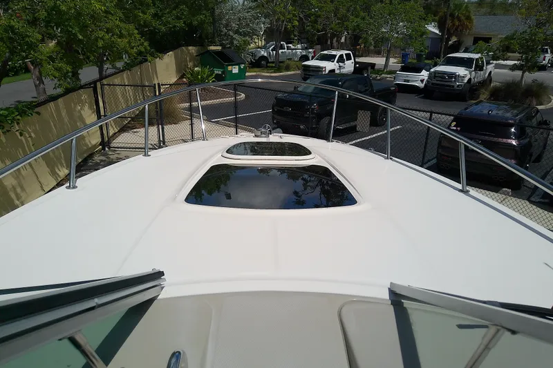 Slide: The Image of 2012 Sea Ray Sundancer 280 boat deck with sunroof, parked near vehicles. - 29