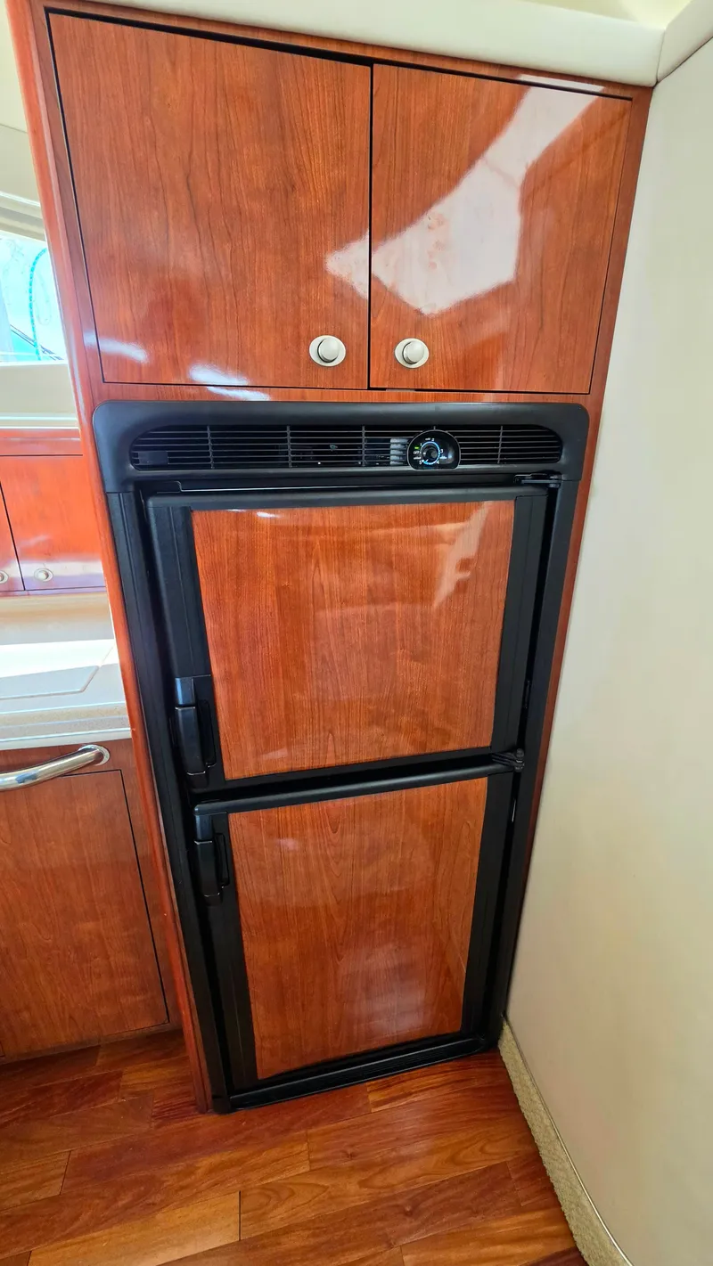 Slide: The Image of A sleek wooden cabinet with a built-in refrigerator in a yacht kitchen. - 25