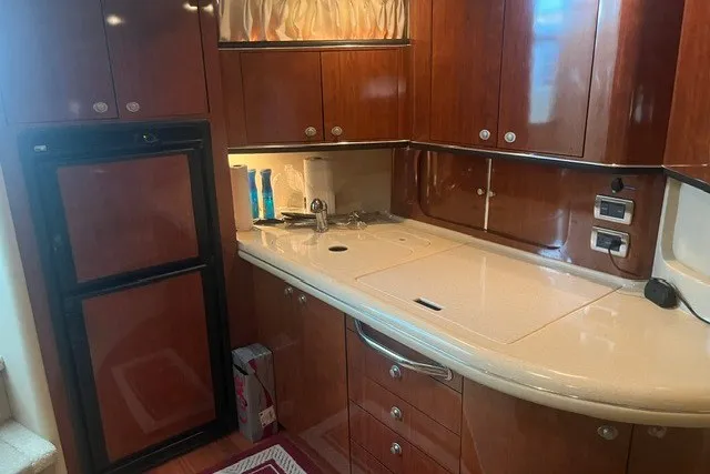 Slide: The Image of 2005 Sea Ray Sundancer 260 interior kitchen with wood cabinets and compact appliances. - 24