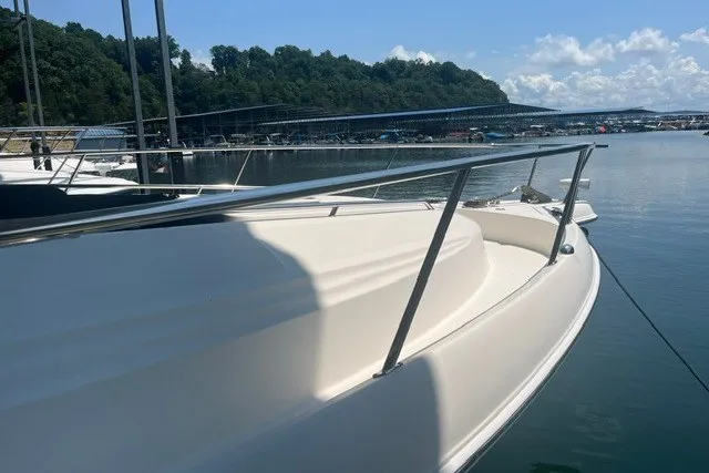 Slide: The Image of 2005 Sea Ray Sundancer 260 docked at a marina, surrounded by calm water and trees. - 2