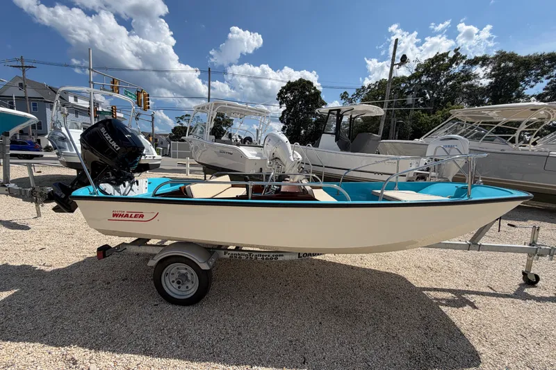 The Image of 1969 Boston Whaler 13 Super Sport boat on trailer, displayed outdoors under a sunny sky. - 1