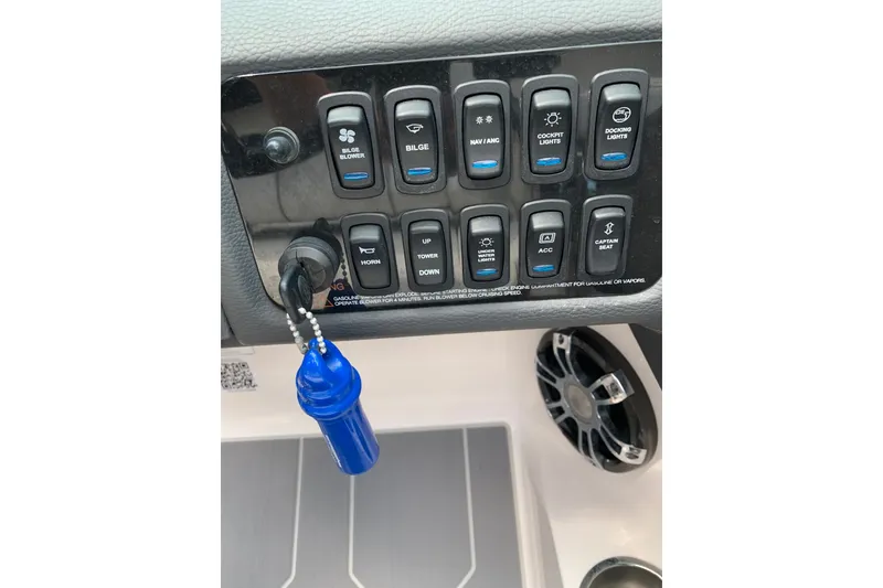 Slide: The Image of Control panel of a 2020 Regal LS6 Surf boat with various switches and a blue keychain. - 66