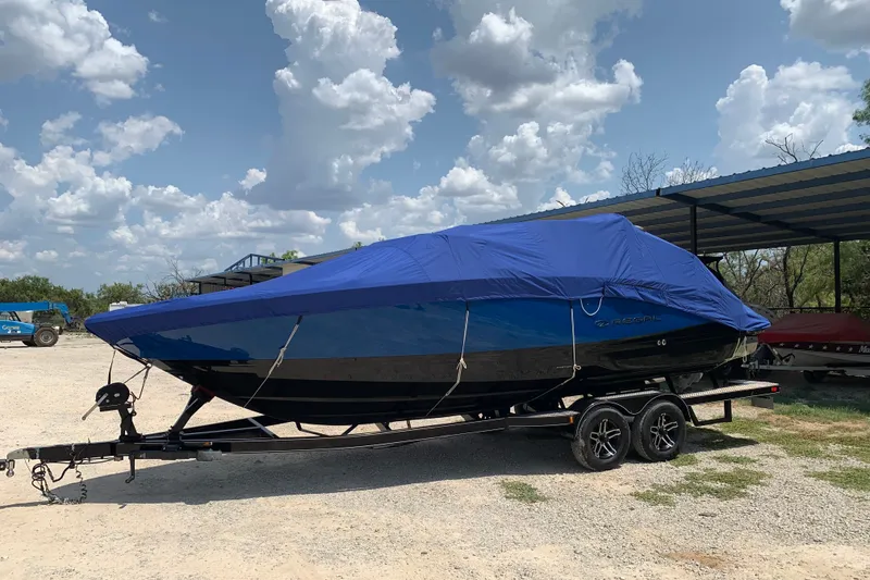 Slide: The Image of 2020 Regal LS6 Surf boat covered, parked on a trailer under a cloudy sky. - 75
