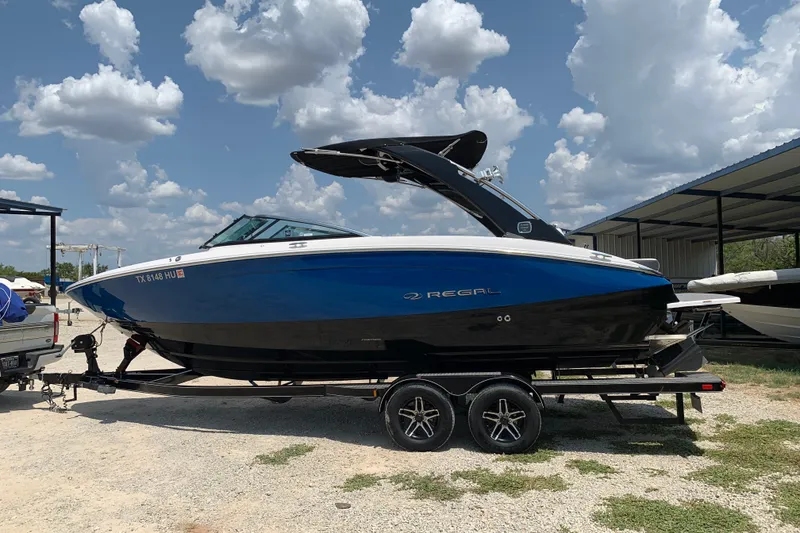 Slide: The Image of 2020 Regal LS6 Surf boat on trailer under a partly cloudy sky. - 2