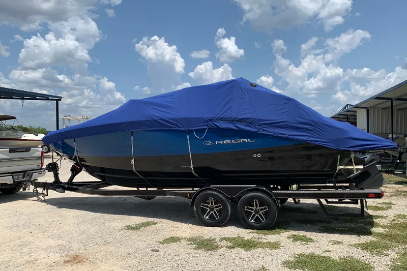 Slide: The Image of 2020 Regal LS6 Surf boat covered on trailer under a blue sky. - 74